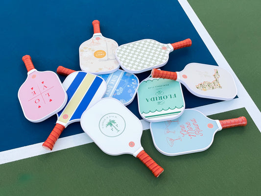 A pile of cute pickleball paddles on a pickleball court