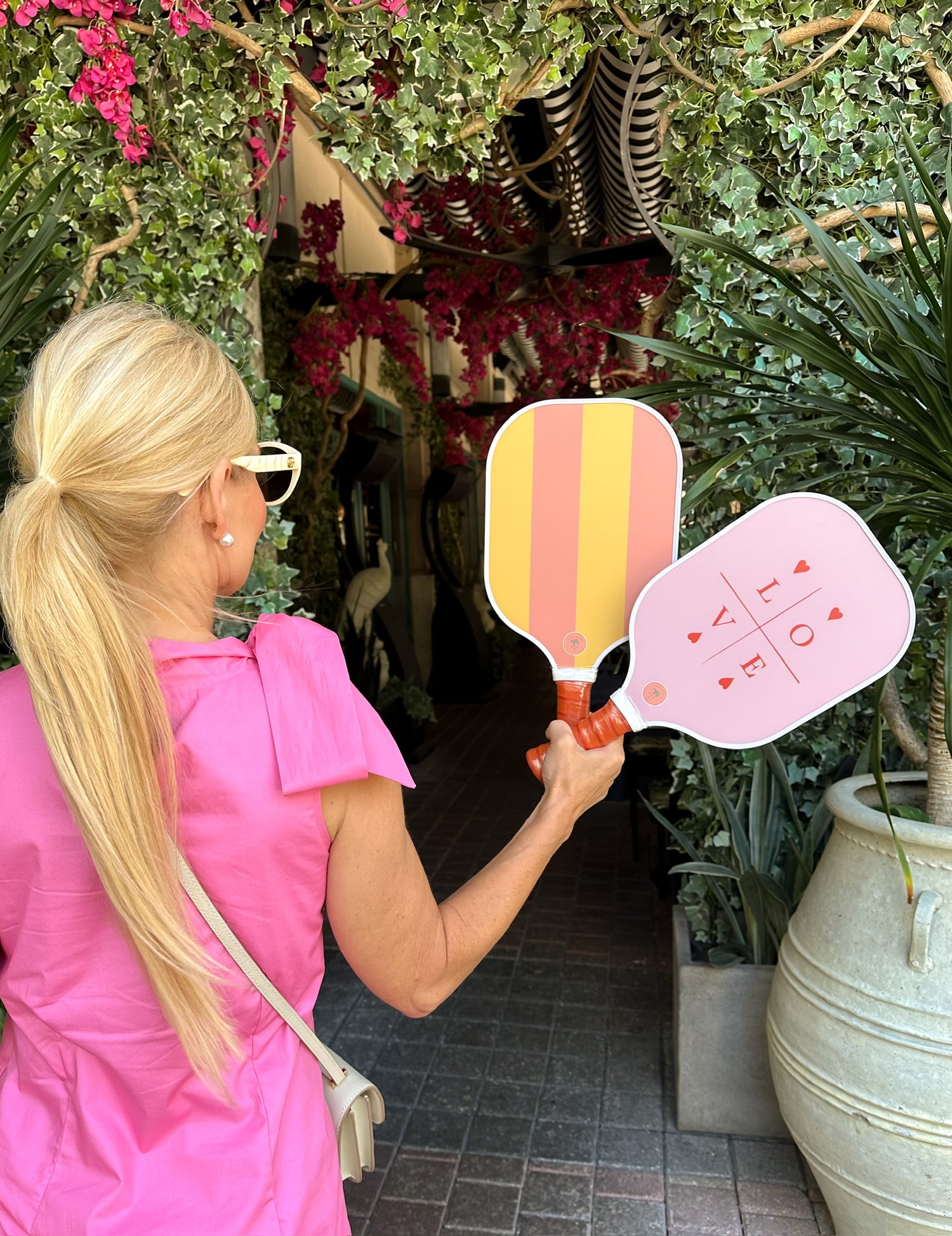 A lady holding up two cute pickleball paddles