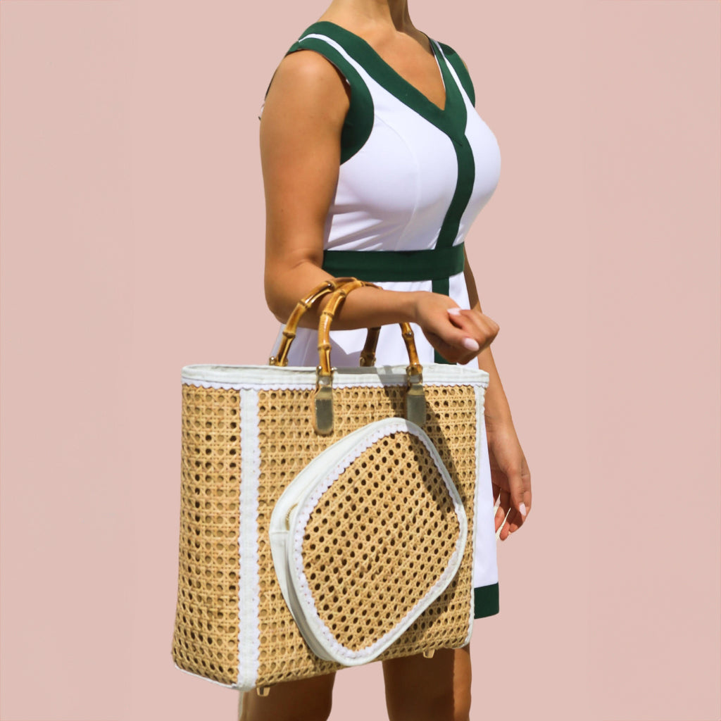 A woman wearing a white and green pickleball dress holding a pickleball bag