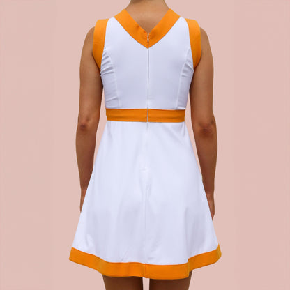 A woman wearing a white and orange pickleball dress