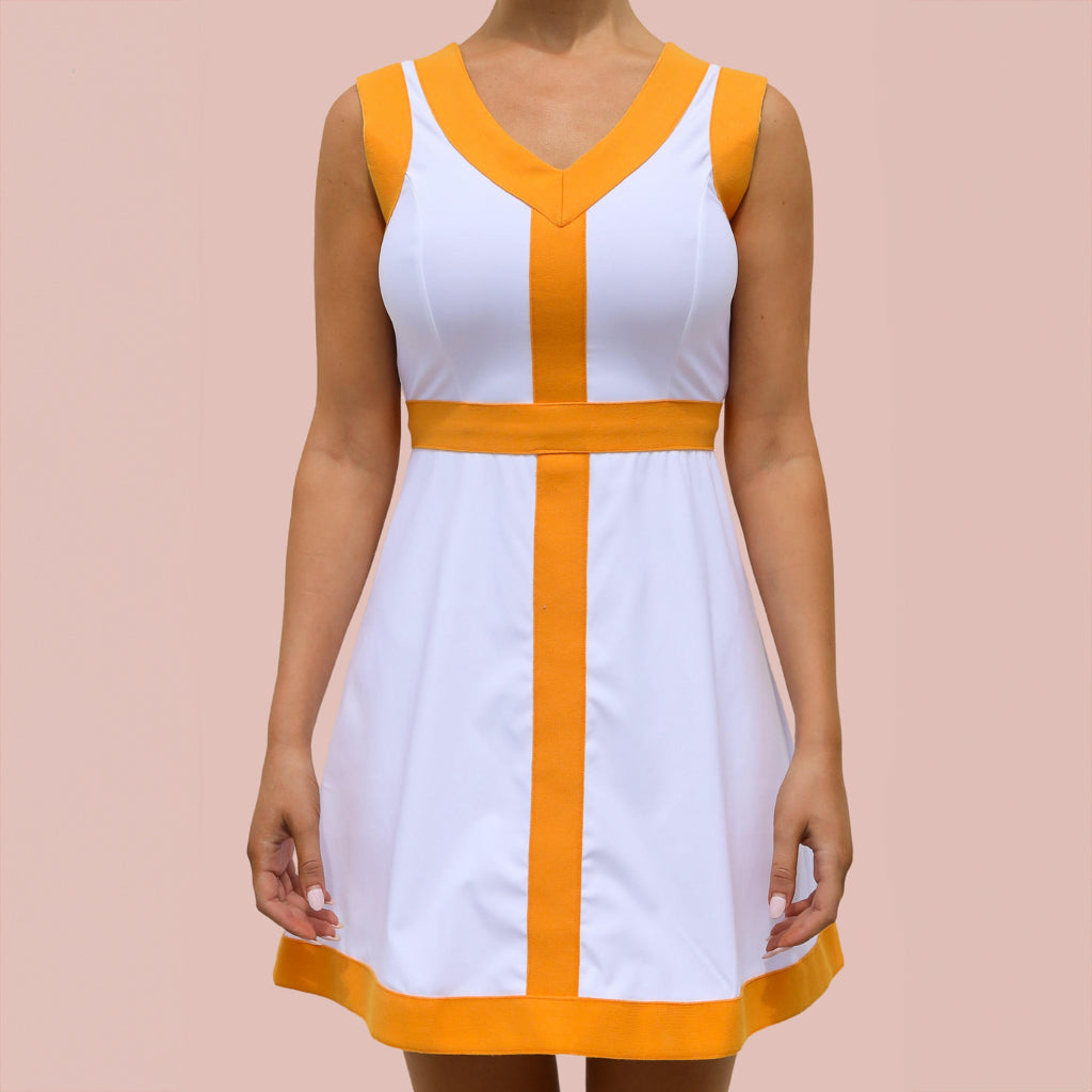 A woman wearing a white and orange pickleball dress