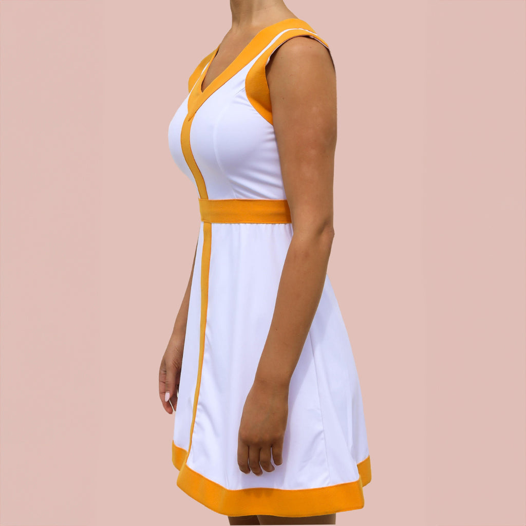 A woman wearing a white and orange pickleball dress