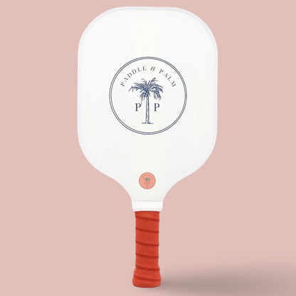 The back of a cute pickleball paddle with a blue paddle and palm logo