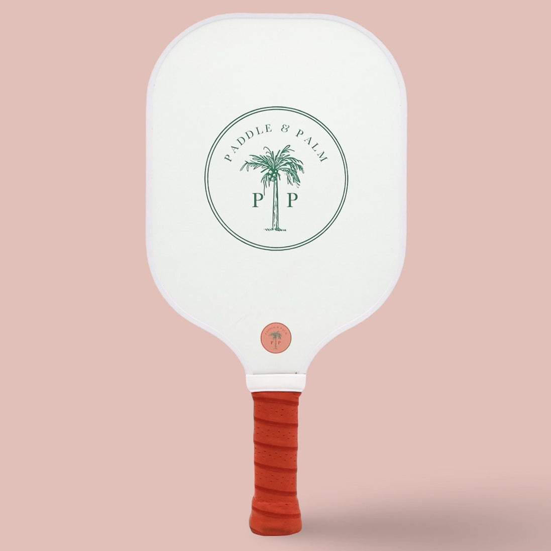 The back of a cute pickleball paddle with a green paddle and palm logo