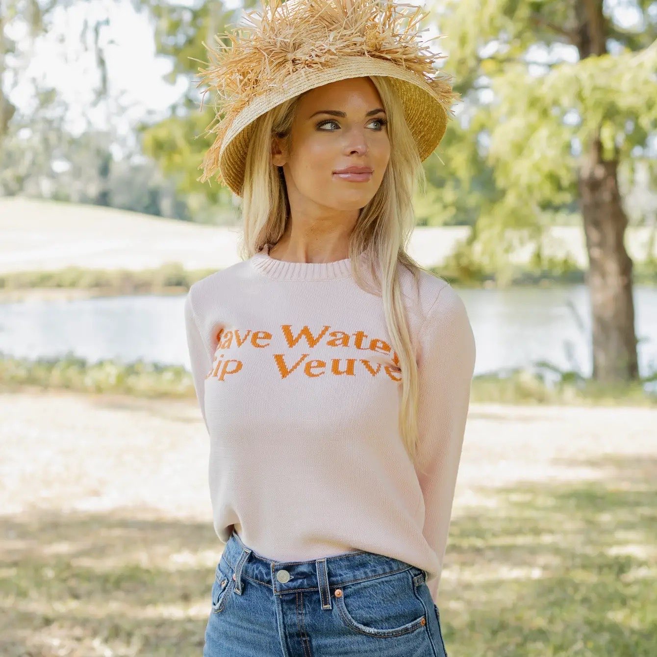 Woman wearing a sweater with text outdoors by a lake